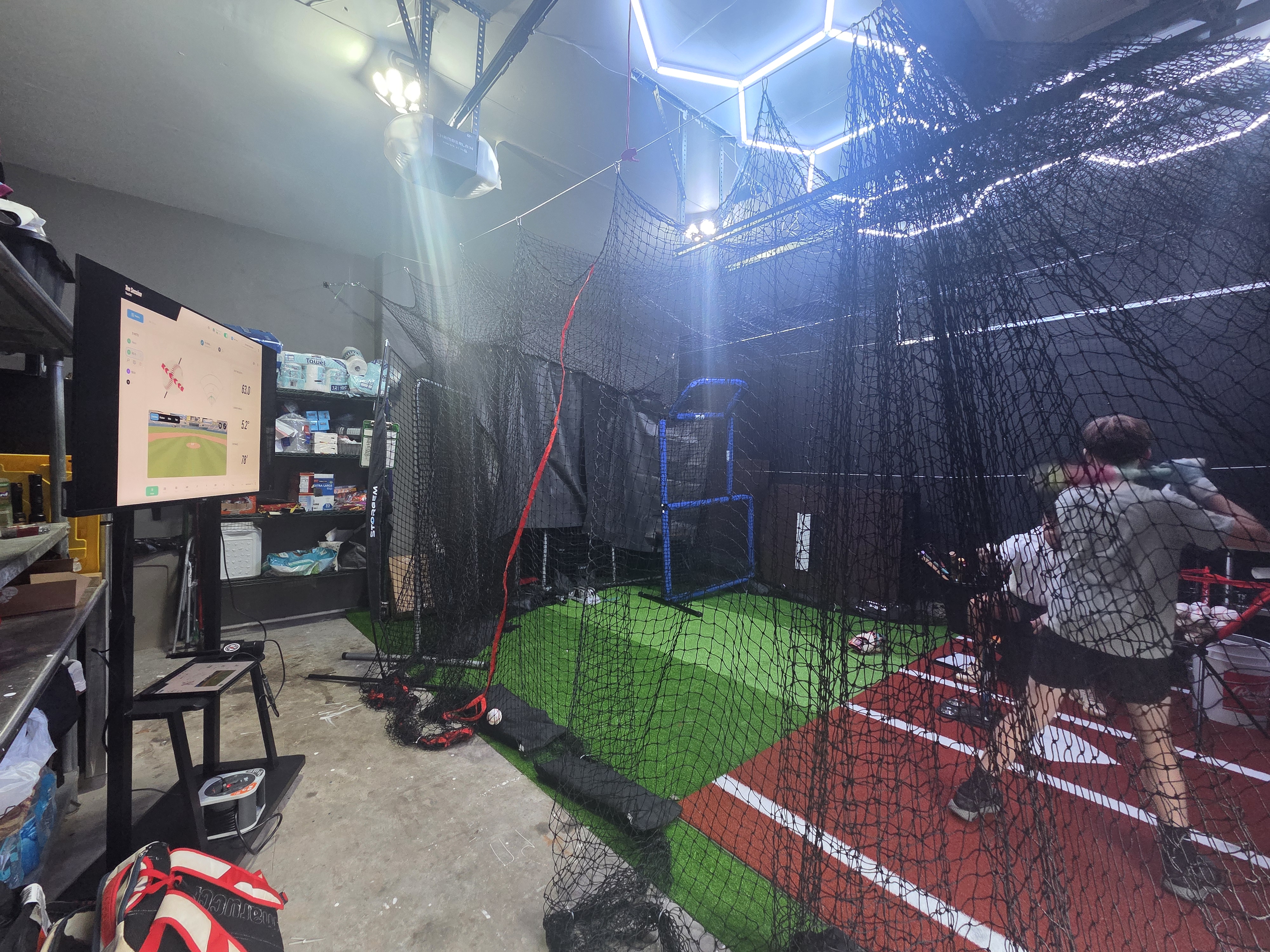 A monitor on a stand beside the Garage Lab cage during a session.